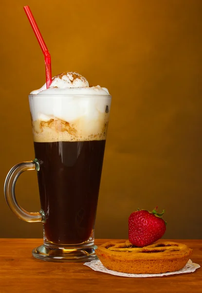 Vaso de café cóctel con tarta sobre tapete y fresa sobre fondo marrón — Foto de Stock