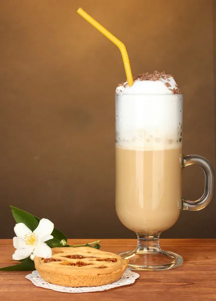 Vaso de café cóctel con tarta sobre tapete y flor sobre fondo marrón —  Fotos de Stock