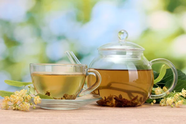 Theepot en cup met linden thee en bloemen op houten tafel in tuin — Stockfoto