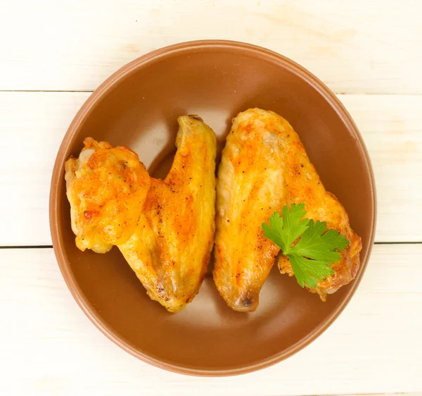 Pečená kuřecí křídla s petržel v talíř na bílém pozadí dřevěné detail — Stock fotografie