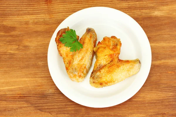 Pečená kuřecí křídla s petržel v talíř na detail dřevěné pozadí — Stock fotografie