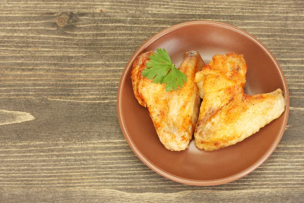 Roasted chicken wings with parsley in the plate on wooden background close-up — Stock Photo, Image