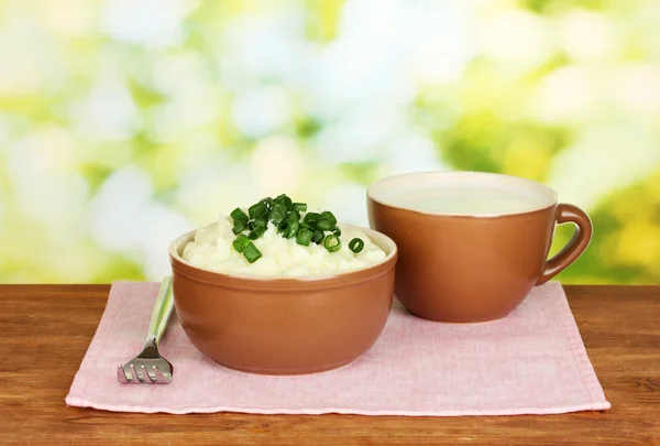 Kartoffelpüree in Schüssel und Tasse mit Milch auf bunter Serviette auf Holzgrund — Stockfoto