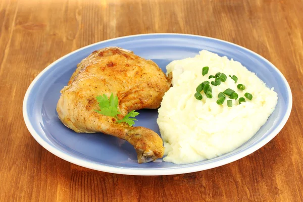 Roasted chicken leg with mashed potato in the plate on wooden table close-up Stock Photo