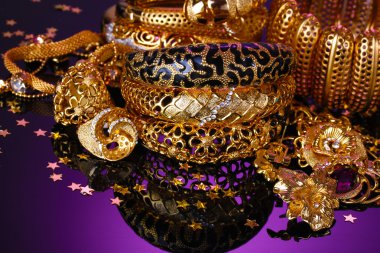 Beautiful golden jewelry on purple background clipart