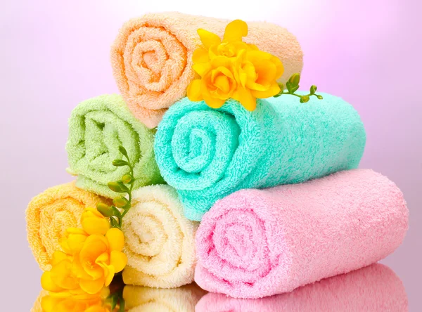 Colorful towels and flowers on purple background — Stock Photo, Image