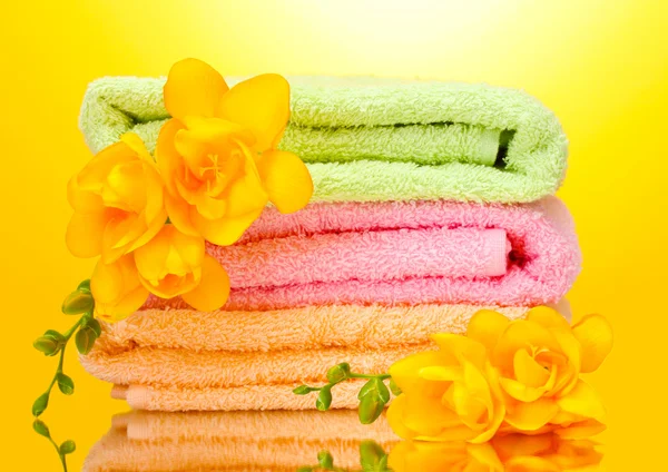 Barevné ručníky a květiny na žlutém podkladu — Stock fotografie