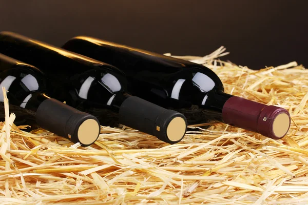 Бутылки отличного вина на сене на коричневом фоне — стоковое фото