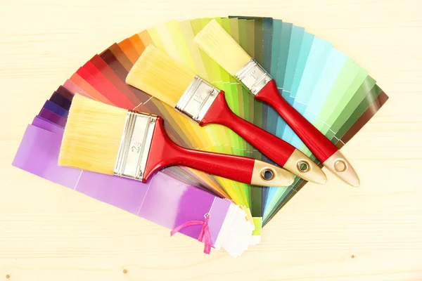 Pincéis de pintura e paleta brilhante de cores sobre fundo de madeira — Fotografia de Stock