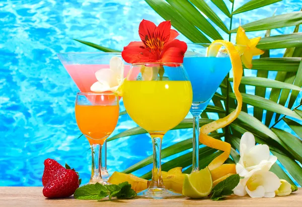 Egzotik kokteyller ve mavi deniz arka plan üzerinde masaya çiçek — Stok fotoğraf