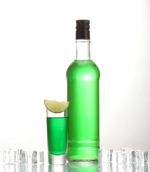 Botella y vaso de absenta con cal y hielo aislados en blanco — Foto de Stock