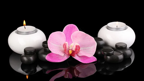 Spa kamienie z orchidea kwiat i świece na czarnym tle — Zdjęcie stockowe