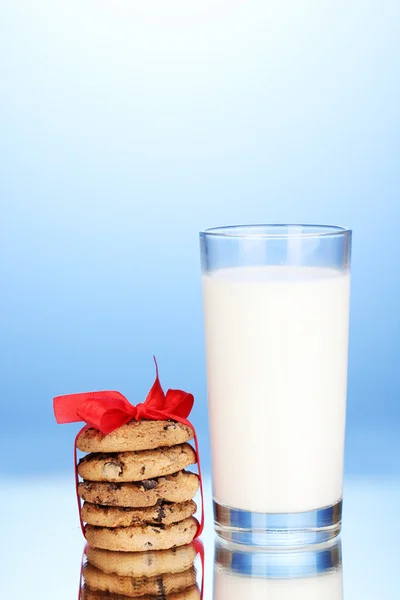 Vaso de leche y galletas sobre fondo azul —  Fotos de Stock