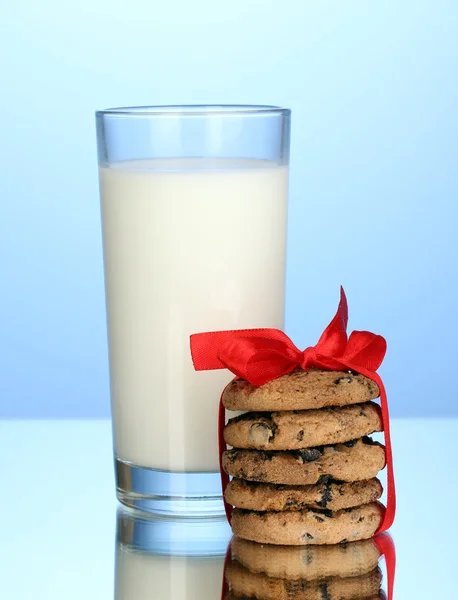 Vetro di latte e biscotti su sfondo blu — Foto Stock