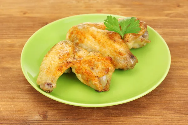Ali di pollo arrosto con prezzemolo nel piatto su fondo di legno primo piano — Foto Stock