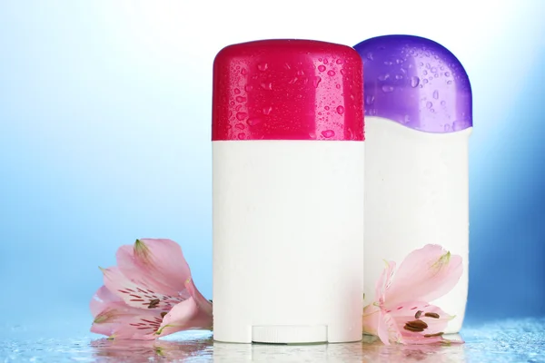 Dezodoranty z kwiatami na niebieskim tle — Zdjęcie stockowe