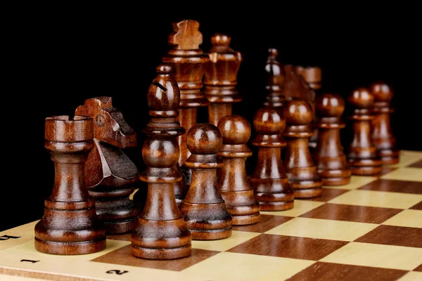 Schackbräde med schackpjäser isolerade på svart — Stockfoto
