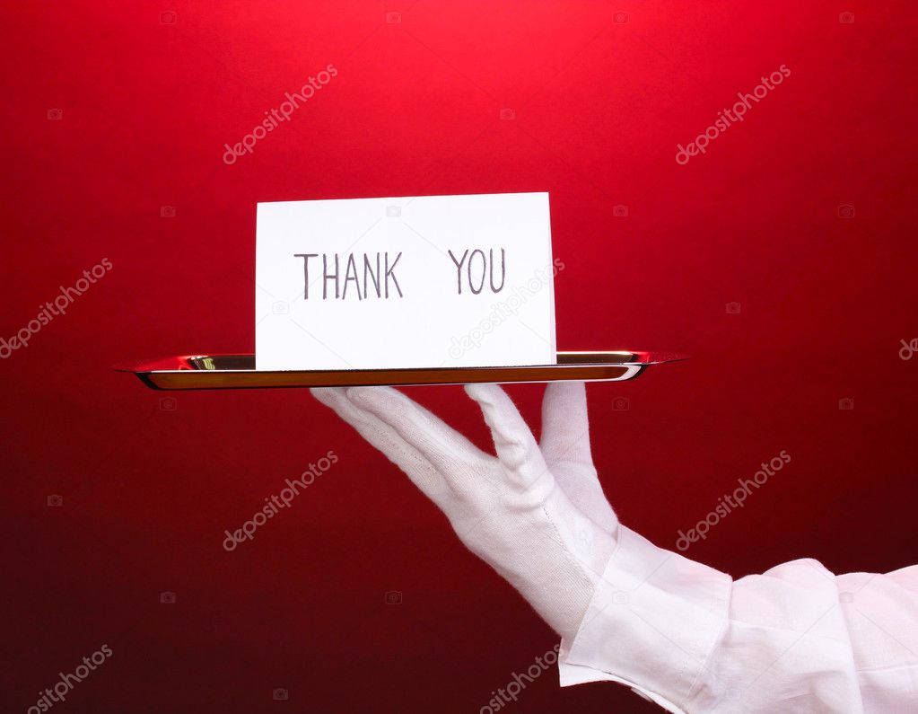 Hand in glove holding silver tray with card saying thank you on red background