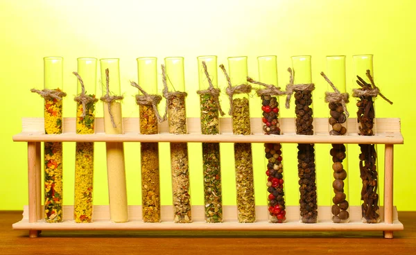 Varie spezie in tubi su tavolo di legno su sfondo verde — Foto Stock