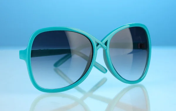 Occhiali da sole blu delle donne alla moda su sfondo colorato luminoso — Foto Stock