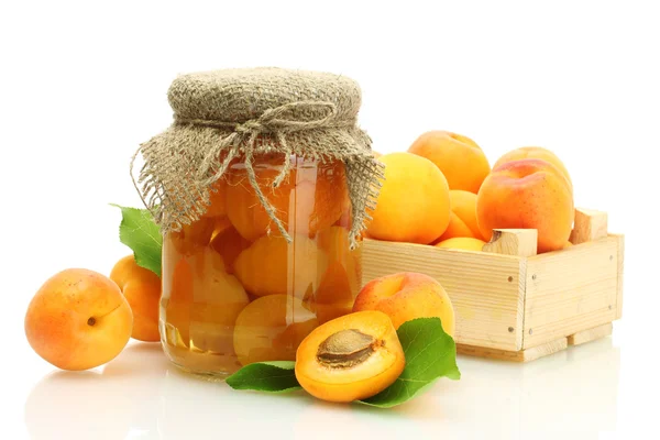 Aprikosendosen im Glas und frische Aprikosen in Holzkiste isoliert auf weiß — Stockfoto