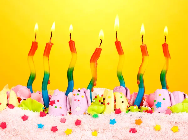Tort urodzinowy z świece na żółtym tle — Zdjęcie stockowe