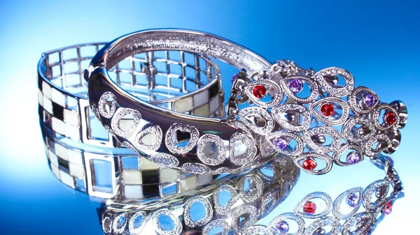 Beautiful silver bracelets on blue background — Stock Photo, Image