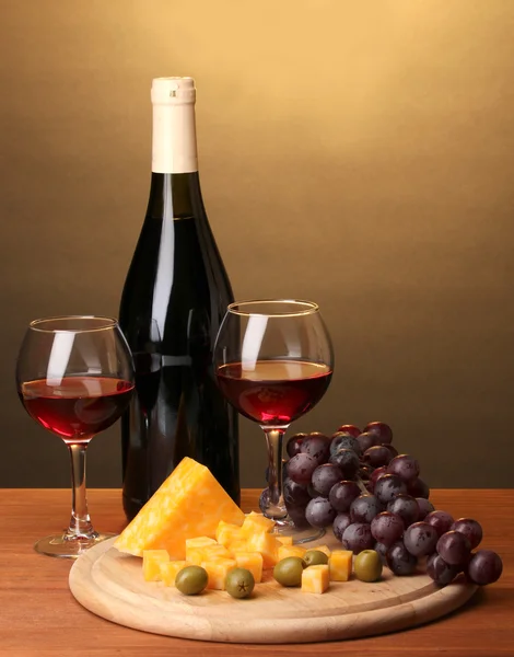 Botella de gran vino con gafas de vino y queso sobre mesa de madera sobre fondo marrón — Foto de Stock