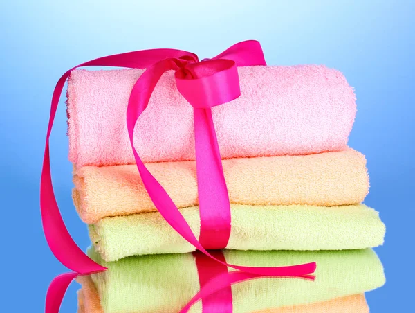 Colorful towels with ribbon on blue background — Stock Photo, Image