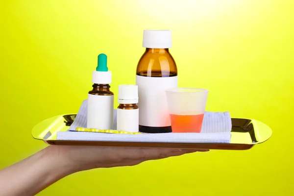 Hand holding tray with medicines on green background — Stock Photo, Image