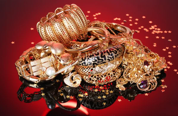 Belas jóias douradas no fundo vermelho — Fotografia de Stock