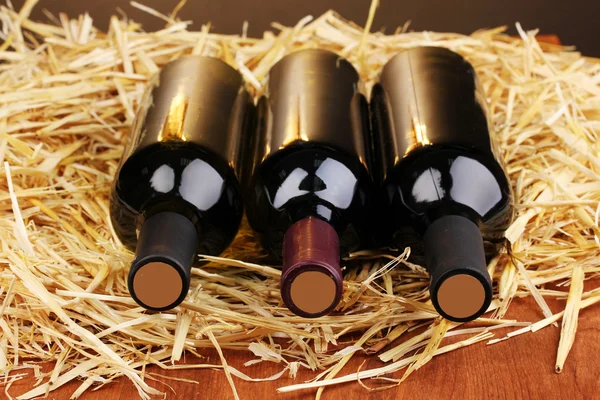 Бутылки отличного вина на сене на деревянном столе — стоковое фото