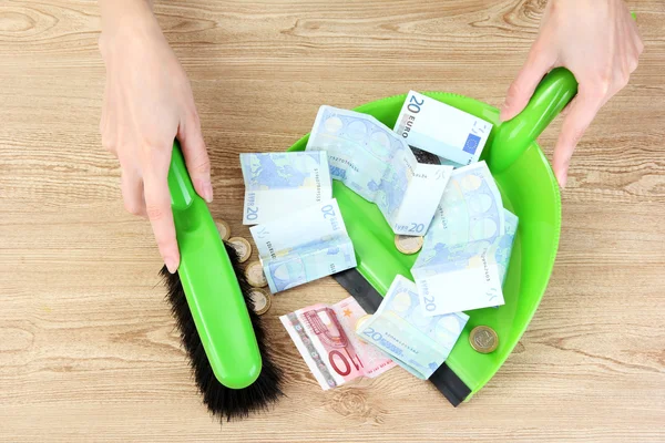 Sweeps money in the shovel on wooden background close-up — Stock Photo, Image