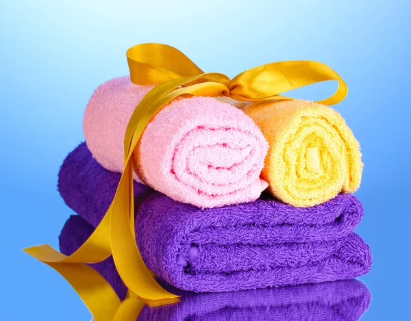 Colorful towels with ribbon on blue background — Stock Photo, Image