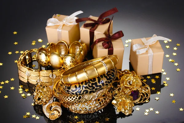 Schöner Goldschmuck und Geschenke auf grauem Hintergrund — Stockfoto
