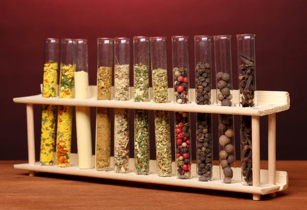 Various spices in tubes on wooden table on red background — Stock Photo, Image