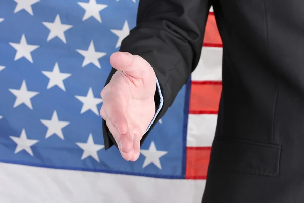 stock image Businessman giving his hand for a handshake on American flag background