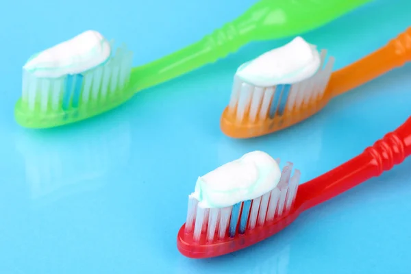 Toothbrushes with paste on blue background — Stock Photo, Image