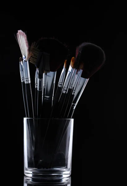 Pincéis de maquiagem em copo de vidro no fundo cinza — Fotografia de Stock