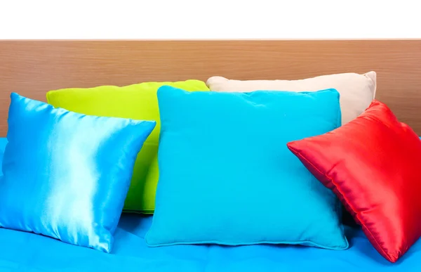 Jasne poduszki na łóżku na białym tle — Zdjęcie stockowe