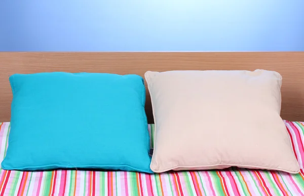 Helle Kissen auf dem Bett auf blauem Hintergrund — Stockfoto