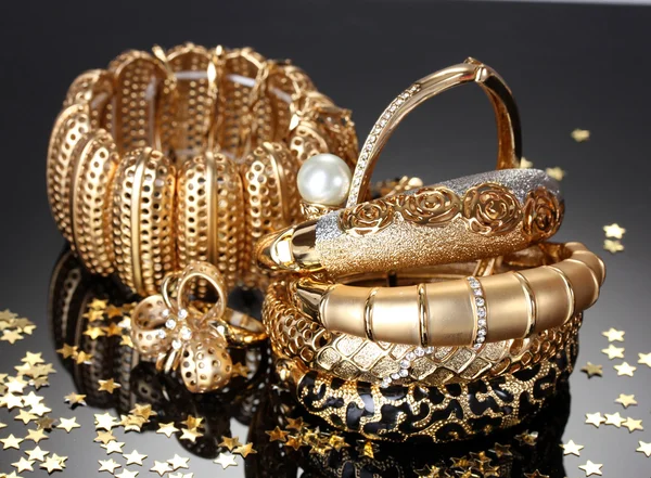 Krásné zlaté šperky na šedém pozadí — Stock fotografie