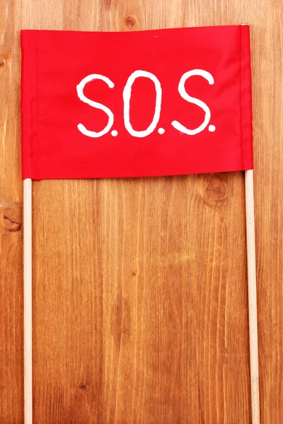 SOS sinal escrito em pano vermelho no fundo de madeira — Fotografia de Stock
