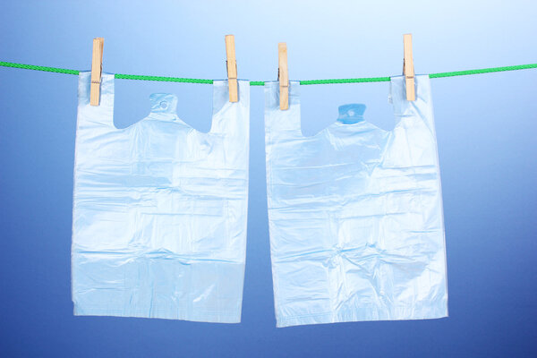 Целофановые мешки висят на веревке на синем фоне
