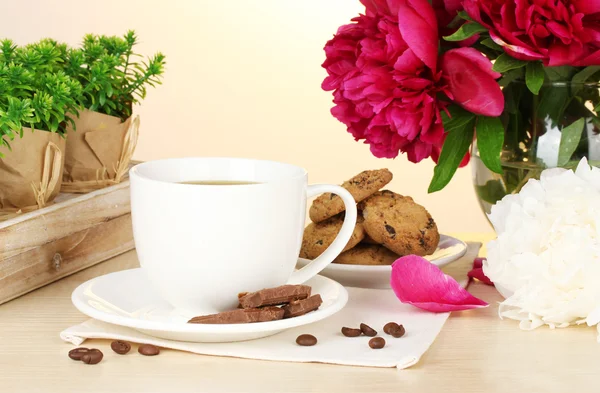 Kopp kaffe, kakor, choklad och blommor på bord i café — Stockfoto