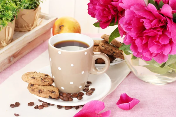 Kopp kaffe, kakor, apple och blommor på bord i café — Stockfoto