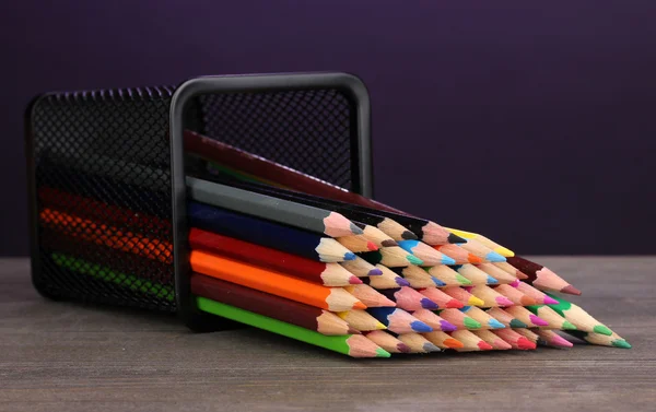 在紫罗兰色的背景上的木桌上的玻璃颜色铅笔 — 图库照片