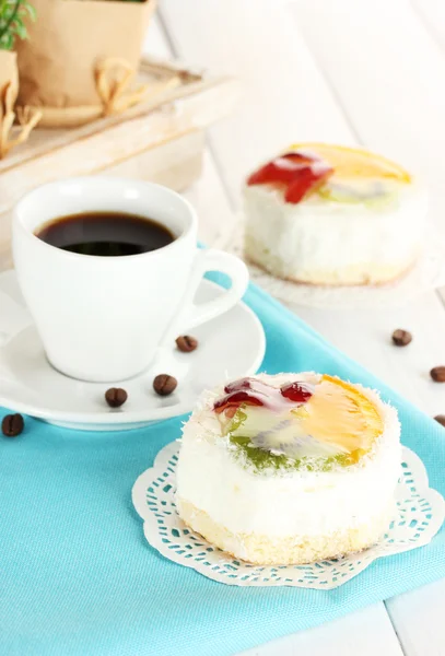 Filiżankę kawy i słodkie ciasta z owocami na drewnianym stole — Zdjęcie stockowe
