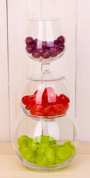 Цветные конфеты в стаканах на деревянном фоне — стоковое фото