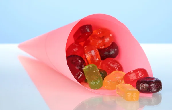 Sabrosos caramelos coloridos en bolsa brillante sobre fondo azul de cerca —  Fotos de Stock